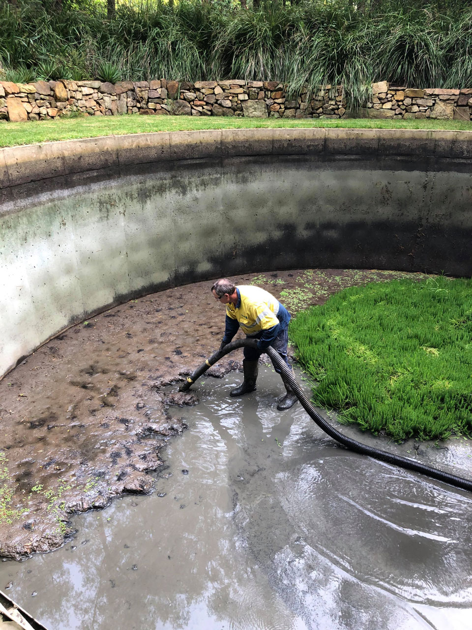 Wet vacuuming of water and waste from a rainwater tank being demonstrated by a member of the South Vac crew.